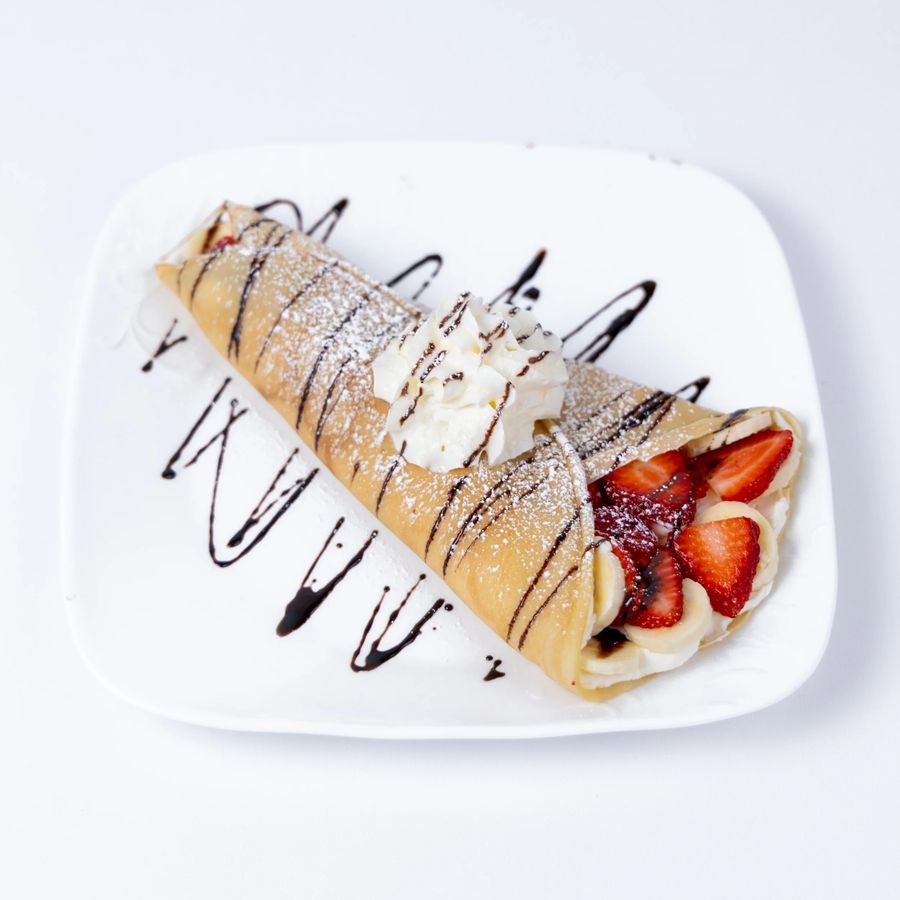 Strawberry crepe with whipped cream and chocolate drizzle